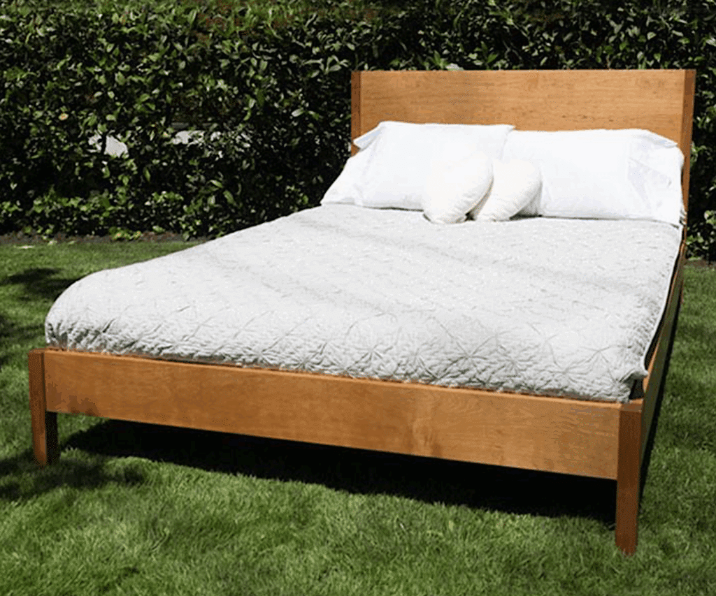 a bed with pillows on it in a grassy field