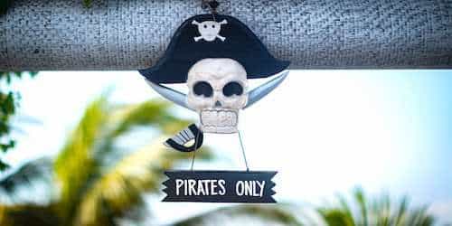 A white pirate skull holding a sign that reads "pirates only"