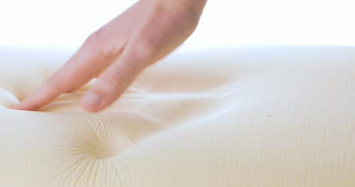 a close-up of a hand touching memory foam