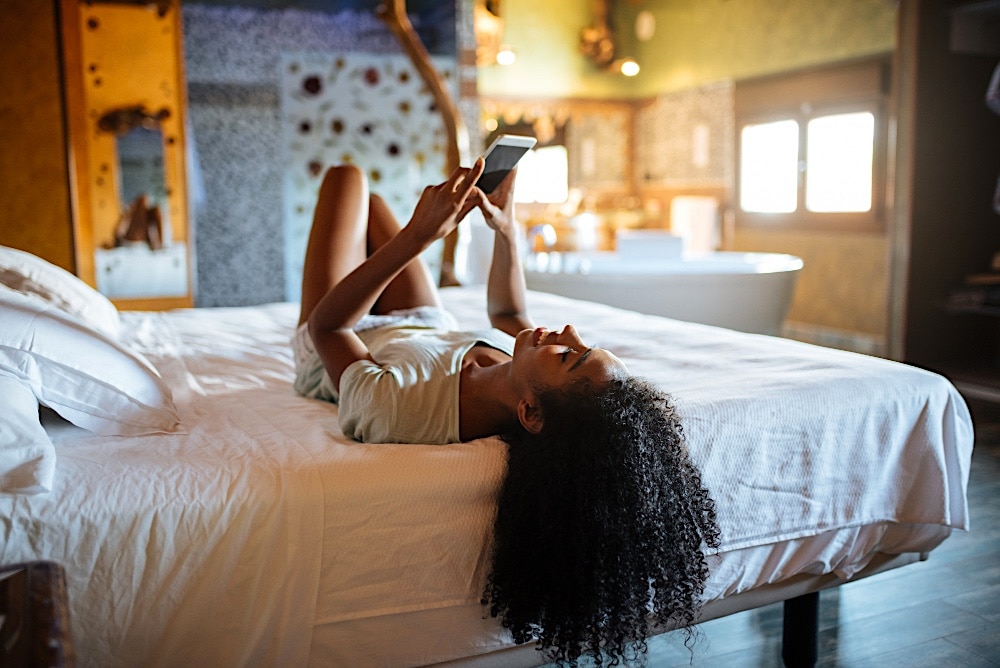 a woman lying on a bed looking at a phone