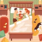 a man and woman lying in bed with a baby and a dog