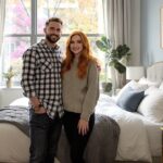 a man and woman standing next to their bed